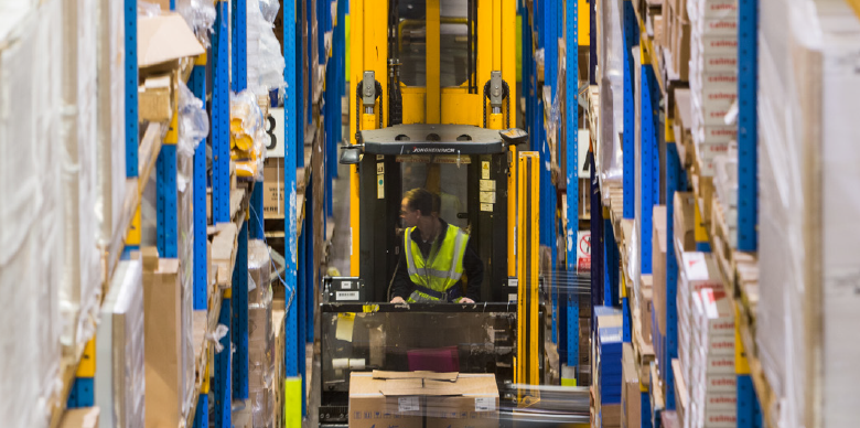 This image: an illustrative photo of an employee working in a logistics warehouse. The map: the map has been replaced with a green triangular graphic with the words 'Hinckley National Rail Freight Interchange: Change for the good'. From each corner of the triangle there is a green button which, when clicked on, shows more information about the positive benefits of HNRFI: jobs, delivering infrastructure, and green agenda.